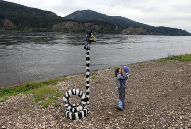 A boy takes a picture with a Soviet-made film camera of an art installation on a bank of the Yenisei River in the village of Ovsyanka, some 24km (15 miles) south of Russia's Siberian city of Krasnoyarsk, August 17, 2013. (Photo by Ilya Naymushin/Reuters)