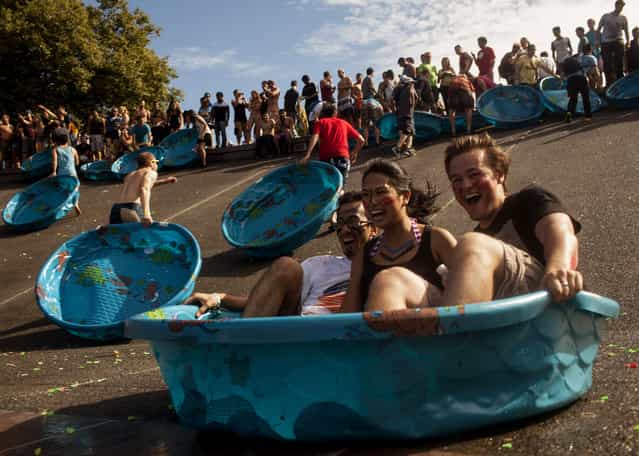 Participants slide down a concrete embankment at the International Fountain, after a Guinness World Records attempt at the largest water balloon fight held in Seattle Center in Seattle, Washington, August 17, 2013. (Photo by Matt Mills McKnight/Reuters)
