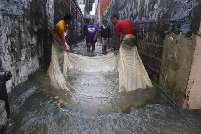 Residents use a mosquito net to catch fish along a flooded alley in a residential district in Bacoor, Cavite near Manila, August 20, 2013. Monsoon rains reinforced by a tropical storm flooded half the Philippine capital in just 24 hours, triggering landslides and killing at least seven people, officials said on Tuesday. (Photo by Erik De Castro/Reuters)