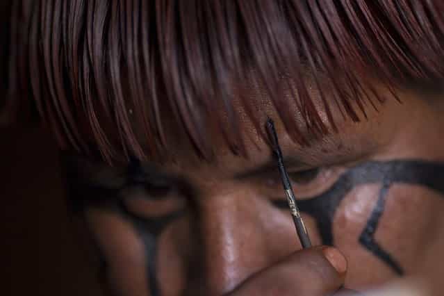 A Waura Indian man paints his face to participate in this year's [quarup], a ritual held over several days to honour in death a person of great importance to them, in the Xingu National Park, Mato Grosso State, August 24, 2013. This year the Waura tribe honoured their late cacique (chief), Atamai, who died in 2012, for his work creating the Xingu Park and his important contribution in facilitating communication between white Brazilians and Indians. (Photo by Ueslei Marcelino/Reuters)