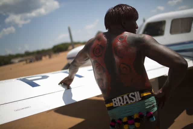 A Waura Indian leans on the wing of a small plane during this year's [quarup], a ritual held over several days to honour in death a person of great importance to them, in Xingu National Park, Mato Grosso State, August 25, 2013. This year the Waura tribe honoured their late cacique (chief) Atamai, who died in 2012, for his work creating the Xingu Park and his important contribution in facilitating communication between white Brazilians and Indians. (Photo by Ueslei Marcelino/Reuters)