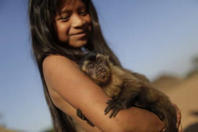 A Waura Indian girl holds a pet monkey during this year's [quarup], a ritual held over several days to honour in death a person of great importance to them, in Xingu National Park, Mato Grosso State, August 25, 2013. This year the Waura tribe honoured their late cacique (chief) Atamai, who died in 2012, for his work creating the Xingu Park and his important contribution in facilitating communication between white Brazilians and Indians. (Photo by Ueslei Marcelino/Reuters)