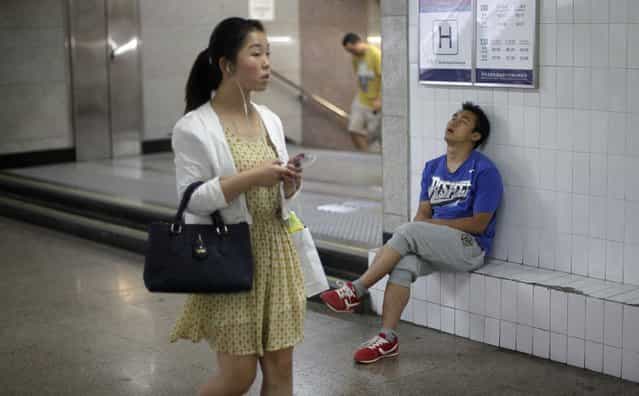A man sleeps as a woman walks past an entrance to a subway station at an underground passage in central Beijing, June 4, 2013. (Photo by Barry Huang/Reuters)