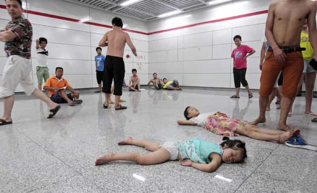 Children sleep on the floor of the Qiaosi subway station in Hangzhou, Zhejiang province July 25, 2013. More than 600 people cooled off inside the subway station as temperatures in the city hit a high of 40 degrees Centigrade during a regional power outage on Thursday. (Photo by Reuters/Stringer)