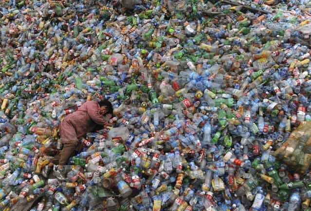 A laborer rests on piles of plastic bottles at a recycling center in Jiaxing, Zhejiang province November 6, 2011. (Photo by Reuters)