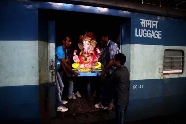 A clay idol of the Hindu god Ganesh is carried onto a passenger train before being transported to a place of worship in Mumbai, on September 1, 2013. Ganesh Chaturthi, celebrated as the birthday of Lord Ganesha, begins September 9. The idols will be immersed in bodies of water at the end of the festival. (Photo by Rafiq Maqbool/Associated Press)