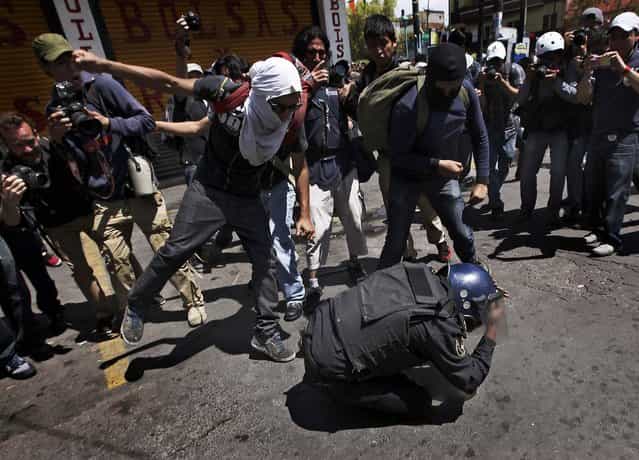A policeman is beaten up by a group of protesters during a march in Mexico City, on September 1, 2013. The officer was later taken away by colleagues. Teachers, anarchists and other groups protested against proposed energy and education reforms. (Photo by Marco Ugarte/Associated Press)