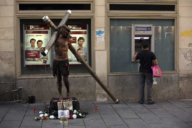 A performer dressed as Jesus Christ stands next to a man using an ATM machine in Madrid September 4, 2013. Spain's economy has been in recession since mid-2011, the second since a decade-long property bubble burst in 2008, though the government has said it expects to see quarterly growth in the second half of 2013. (Photo by Susana Vera/Reuters)