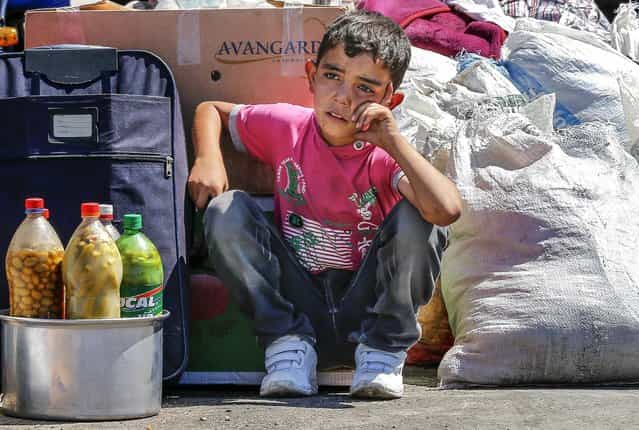 A Syrian boy sits beside his family's belongings as they wait for a vehicle to pick them up after entering the Turkish border gate, on September 6, 2013. The U.N. refugee agency UNHCR said that a near tenfold increase over the past 12 months in the rate of refugees crossing Syria's borders into Turkey, Iraq, Jordan and Lebanon – to a daily average of nearly 5,000 men, women and children – had pushed the total living abroad above two million. (Photo by Umit Bektas/Reuters)