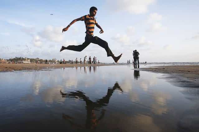 A man jumps over a water stream on a beach along the Arabian Sea in Mumbai, India, on September 3, 2013. (Photo by Danish Siddiqui/Reuters)