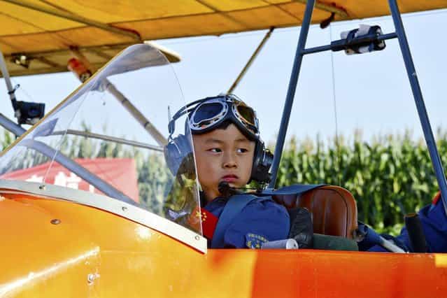 5 year-old He Yide sits in a glider before flying the plane in Guan county, Hebei province, China, on September 4, 2013. He piloted the plane, accompanied by his coach, from Guan county to Beijing Wildlife Park at a height of 150m (492 feet) and completed the flight in 35 minutes. (Photo by Reuters)