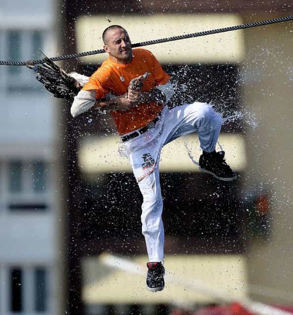 A man attempts to pull the neck off a dead goose while repeatedly being plunged into the water during Antzar Eguna (Day Of The Goose) in the Basque fishing town of Lekeitio, Spain, on September 5, 2013. Geese are hung from a rope over the harbor as participants passing on a boat attempt to grab the animal; those who succeed in pulling the neck off get to keep the goose. (Photo by Vincent West/Reuters)