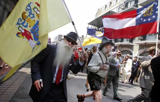 Chris Porrovecchio of Kendall Park, New Jersey ,left, carries the New Jersey state flag during a parade through the French Quarter kicking off the fourth annual Just For Men National Beard and Moustache Championships Saturday, September 7, 2013 in New Orleans. Contestants competed in 18 different categories including Dali, full beard natural and sideburns. (Photo by Susan Poag/AP Photo)
