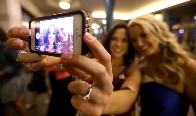Miss America pageant alumni Miss South Dakota Calista Kirby, left, and Miss Rhode Island Kelsey Fournier take a photograph of themselves with a phone before the Miss America 2014 pageant, Sunday, September 15, 2013, in Atlantic City, N.J. The former misses participated in last year's contest in Las Vegas. (Photo by Julio Cortez/AP Photo)