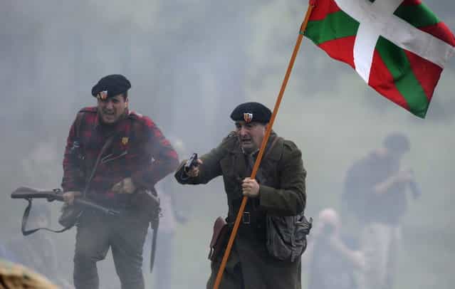 Aitor Esteban, a deputy of the PNV (National Basque Party), holds a gun and an [ikurrina] flag during a re-enactment of the "Battle of Areces" that took place during the Spanish Civil War, in Grullos, north of Spain, September 14, 2013. The re-enactment of the historic 1937 battle was organised by the Frente del Nalon Association. (Photo by Eloy Alonso/Reuters)