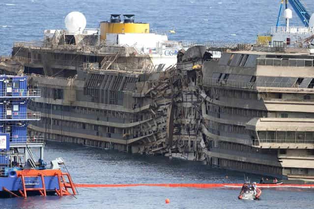 The Costa Concordia is seen after it was lifted upright, on the Tuscan Island of Giglio, Italy, Tuesday, September 17, 2013. The crippled cruise ship was pulled completely upright early Tuesday after a complicated, 19-hour operation to wrench it from its side where it capsized last year off Tuscany, with officials declaring it a [perfect] end to a daring and unprecedented engineering feat. (Photo by Andrea Sinibaldi/AP Photo/Lapresse)