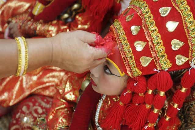 A Nepalese girl wearing a traditional attire receives a red tika on her forehead during the Kumari Puja, a mass worship, at Hanuman Dhoka in Durbar Square in Kathmandu, September 17, 2013. (Photo by Bikash Dware/Reuters)