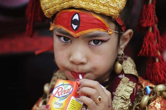 A Nepalese girl wearing a traditional attire drinks juice during the Kumari Puja, a mass worship, at Hanuman Dhoka in Durbar Square in Kathmandu, September 17, 2013. A total of 504 girls under the age of nine from across the country gathered for the mass worship, which is believed to protect them from evil and bring them good luck in future. (Photo by Bikash Dware/Reuters)