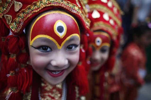 A young Nepalese girl dressed as a Kumari or living Goddess, smiles for camera as she waits for Kumari puja at Hanuman Dhoka, Basantapur Durbar Square in Katmandu, Nepal, Tuesday, Sept 17, 2013. More than hundred girls under the age of nine gathered for Kumari puja, a tradition of worshiping young pre-pubescent girls as manifestations of the divine female energy. The ritual holds a strong religious significance in Newar community. It is a community affair held primarily to save small girls from diseases and bad luck in the years to come. (AP Photo/Niranjan Shrestha)