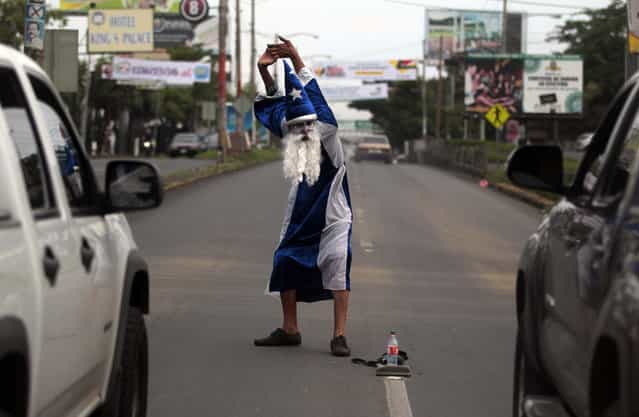 Roberto Castillo, dressed as a magician, performs on a busy street in Managua September 18, 2013. Castillo earns about $3 a day through his street performances. (Photo by Oswaldo Rivas/Reuters)