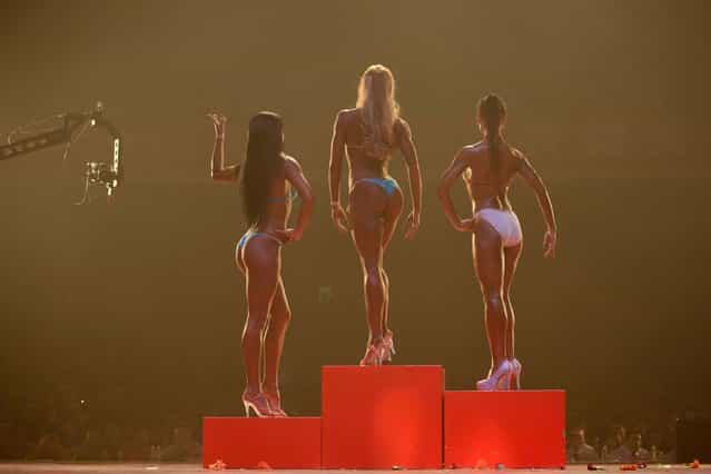 [[Bikini fitness] competitors stand on the podium during a bodybuilding contest in Zhengzhou, Henan province, September 16th, 2013. More than 20 professionals – including a dozen from China – were competing in the Bodybuilding Grand Prix in the central Chinese city for a top prize worth 80,000 yuan (13,000 USD). They were joined by scores of amateurs from across the country, in what event organisers said was a sign of the increasing popularity of muscle building in China. Bodybuilding has at least a century of history in China, but fell out of favor following the Communist revolution in 1949, when competitions were sometimes banned and the sport condemned as western and bourgeois. But it has since enjoyed a resurgence and competitors say the growing number of competitions are boosting the ranks of local professionals. (Photo by Ed Jones/AFP Photo)