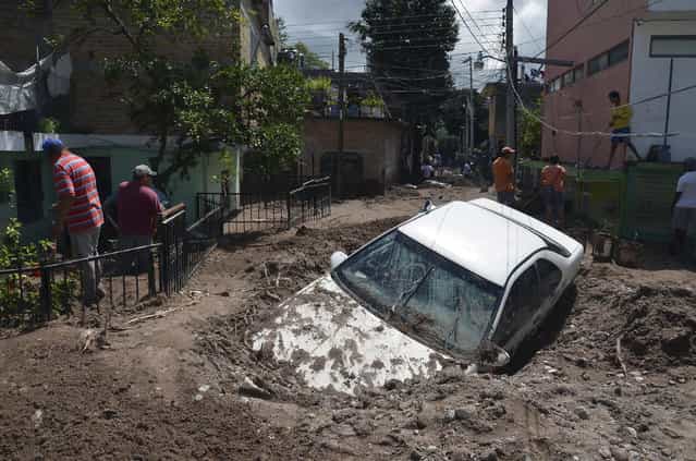 A car lays buried in mud after flooding triggered by Tropical Storm Manuel as residents try to clean up their neighborhood in Chilpancingo, Mexico, Thursday, September 19, 2013. Manuel, the same storm that devastated Acapulco, gained hurricane force and rolled into the northern state of Sinaloa on Thursday before starting to weaken. (Photo by Alejandrino Gonzalez/AP Photo)