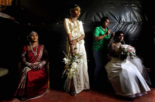 Former Tamil Tiger female rebel fighters and brides Nadarasa Sukirtha (L) and Premarathnam Sugandhini (C) look on as Jayarasa Merry Babila, an ethnic Tamil, get ready for a mass wedding in Kilinochchi,Sri Lanka, on September 18, 2013.Three ex-rebel couples who have been rehabilitated by the Sri Lankan Civil Defence Force were married as part of the government's rehabilitation program. (Photo by Dinuka Liyanawatte/Reuters)