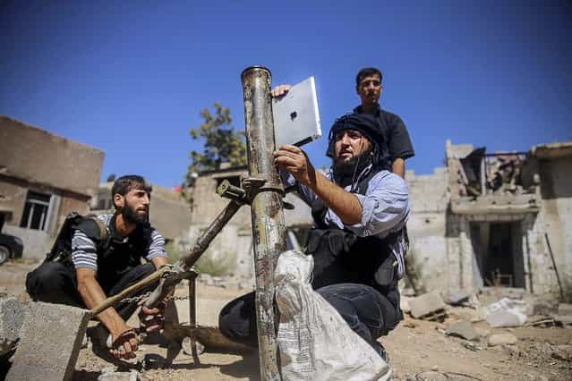 A member of the [Ansar Dimachk] Brigade, part of the [Asood Allah] Brigade which operates under the [Free Syrian Army], uses an iPad during preparations to fire a homemade mortar at one of the battlefronts in Jobar, Damascus September 15, 2013. (Photo by Mohamed Abdullah/Reuters)