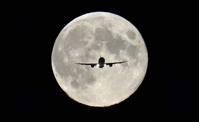 A passenger aircraft, with the full [Harvest Moon] seen behind, makes its final approach to landing at Heathrow Airport in London, on September 19, 2013. The Harvest Moon is a name for the full moon that is closest to the autumn equinox, and at a time when farmers would traditionally be harvesting crops. (Photo by Toby Melville/Reuters)