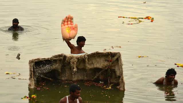A man holds the hand of an idol of the Hindu elephant god Ganesh, the deity of prosperity, during idol immersion ceremony in the Hussain Sagar lake during the Ganesh Chaturthi festival in the southern Indian city of Hyderabad September 17, 2013. Ganesh idols are taken through the streets in a procession accompanied by dancing and singing and later immersed in a river or the sea symbolising a ritual seeing-off of his journey towards his abode, taking away with him the misfortunes of all mankind. (Photo by Krishnendu Halder/Reuters)