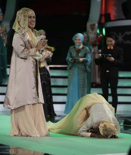 Obabiyi Aishah Ajibola, right, kisses the floor after being named World Muslimah 2013, as runner up Noor Aspasia of Indonesia, left, applauds, during the third Annual Award of World Muslimah in Jakarta, Indonesia, Wednesday, September 18, 2013. The annual pageant, held exclusively for Muslim women, assessed not only contestants' appearance but also their piety and religious knowledge. (Photo by Dita Alangkara/AP Photo)