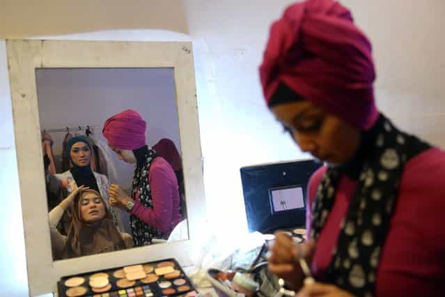 An Indonesian beautician (R) applies make-up on a contestant of the Muslimah World 2013 as they prepare for a grand final during the Muslimah World competition in Jakarta on September 18, 2013. (Photo by Adek Berry/AFP Photo)
