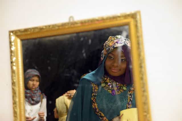 Contestant of the Muslimah World 2013, Obabiyi Aishah Ajibola (C) of Nigeria, is reflected in a mirror checking her make-up while contestants wait for a grand final during the Muslimah World competition in Jakarta on September 18, 2013. (Photo by Adek Berry/AFP Photo)