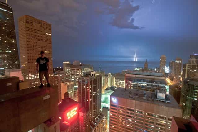 Bradley Garrett stands on the edge of the Ritz-Carlton Chicago as lightning strikes in the distance in Chicago, US. (Photo by Bradley L. Garrett/Barcroft Media)
