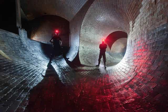 Two urban explorers with their headtorches set to red-beam inside the River Effra, another of London's [lost rivers], in London. (Photo by Bradley L. Garrett/Barcroft Media)