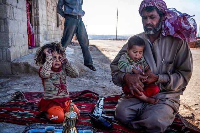A [Free Syrian Army] fighter holds his son outside their home in Habit village, the Syrian central province of Hama, on September 25, 2013. (Photo by Associated Press)