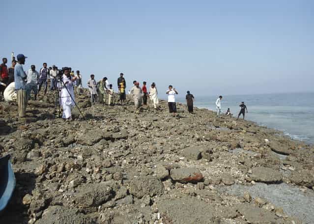 Members of the media and people walk on an island that rose from the sea following an earthquake off Pakistan's Gwadar coastline in the Arabian Sea September 25, 2013. A major earthquake hit a remote part of western Pakistan on Tuesday, killing at least 327 people and prompting the new island to rise from the sea just off the country's southern coast. The earthquake was so powerful that it caused the seabed to rise and create a small, mountain-like island about 600 meters off Pakistan's Gwadar coastline. Television channels showed images of a stretch of rocky terrain rising above the sea level, with a crowd of bewildered people gathering on the shore to witness the rare phenomenon. (Photo by Reuters/Stringer)