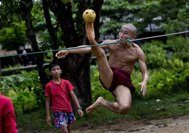 A Buddhist monk kicks a rattan ball during a game of Chinlone in Kawhmu, southwest of Yangon, Myanmar, on September 29, 2013. Chinlone, a combination of sport and dance, is played between two teams, each consisting of six players, passing a rattan ball back and forth with feet, knees and heads. (Photo by Gemunu Amarasinghe/Associated Press)