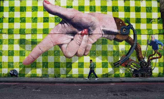 A man walks past a piece of street art in Shoreditch, London, on September 29, 2013. (Photo by Andrew Winning/Reuters)