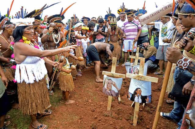 Brazilian natives simulate the burial of politicians during a demonstration in front of the National Congress in Brasilia on October 3, 2013. Indigenous people from several ethnic groups concentrate in the Brazilian capital to demand more support from the federal government during the National Indigenous Mobilization Week. (Photo by Evaristo Sa/AFP Photo)