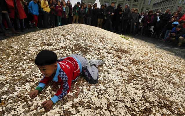 A child plays on a pile of 8,000,00 five cent coins in the centre of the Federal Square during an event organised by the Committee for the initiative [CHF 2,500 monthly for everyone] (Grundeinkommen) in Bern October 4, 2013. The Committee delivered 126,000 signatures to the Chancellery on Friday to propose a change in the constitution to implement their initiative. The initiative aims to have a minimum monthly disposal household income of CHF 2,500 (US$ 2,700) given by the government to every citizen living in Switzerland. (Photo by Denis Balibouse/Reuters)