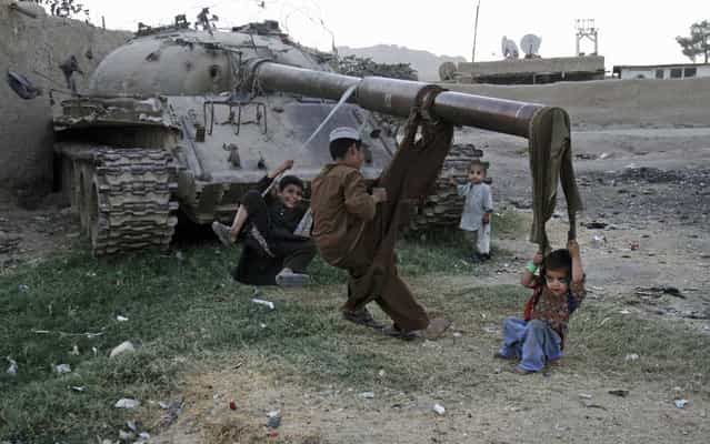 Afghan children play on the remains of a old Soviet tank in the city of Kandahar south of Kabul, Afghanistan, Tuesday, October 1, 2013. (Photo by Allauddin Khan/AP Photo)