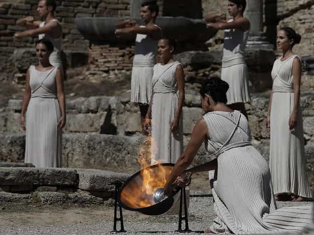 Actress Ino Menegaki as high priestess, lights the Olympic Flame from the sun's rays, during the lighting of the Olympic flame at Ancient Olympia, in west southern Greece on Sunday September 29, 2013. Using the sun's rays at the birthplace of the ancient Olympics, organizers carried out a successful ceremony to light the flame for the 2014 Sochi Winter Olympics February 7–23, 2014 in Russia. (Photo by Dimitri Messinis/AP Photo)