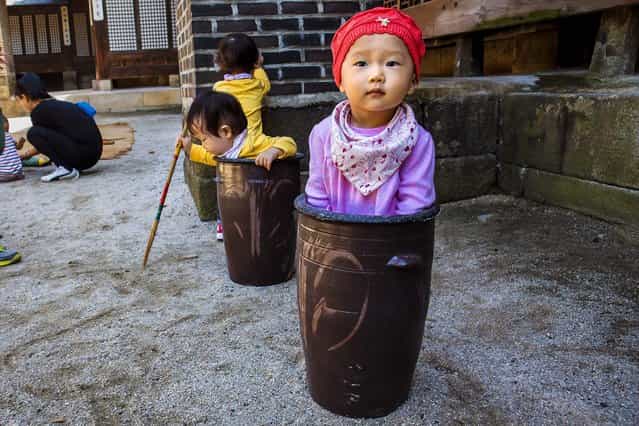 Jung Ha-yoon, 2, appears to be stuck inside a ceramic container while playing with other children at the traditional sports square during the [Taste Korea! Korean Royal Cuisine Festival] held at Unhyeon Palace in Seoul, South Korea, on October 1, 2013. (Photo by Jacquelyn Martin/Associated Press)