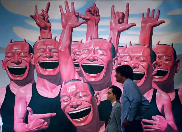 Two men walk past a painting by Chinese artist Yue Minjun titled [Between Men and Animal] during a press preview for a Sotheby's auction in Hong Kong, Wednesday, October 2, 2013. The work is estimated at US$644,650 to 1,031,440 and will be auctioned as part of the autumn sale from October 4–8. (Photo by Vincent Yu/AP Photo)