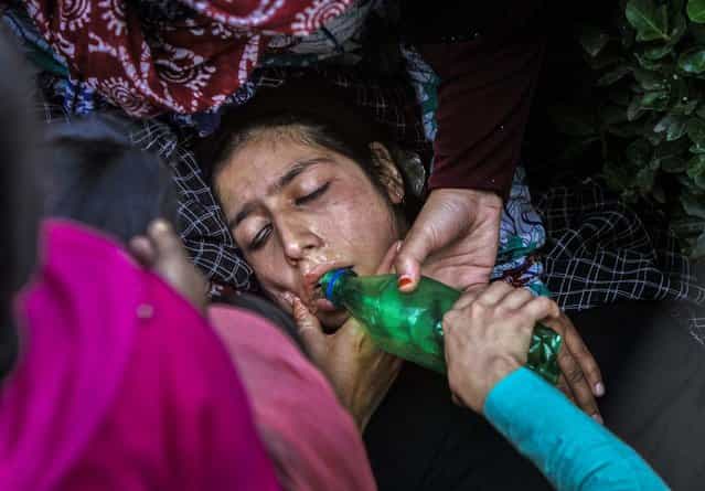Women comfort a teacher and offer her water after a fire broke out in a school building in Srinagar, India, on October 3, 2013. There were no immediate reports of injuries. (Photo by Mukhtar Khan/Associated Press)