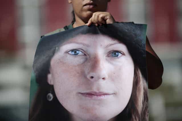 A Greenpeace activist holds a photo of Brazilian Ana Paula Maciel, 31, during a protest in support of activists arrested in Russia, in front of the Russian embassy in Brasilia September 27, 2013. A Russian court ordered 20 Greenpeace activists from around the world to be held in custody for two months pending further investigation over a protest against offshore oil drilling in the Arctic, drawing condemnation and a vow to appeal. Maciel is among the team of activists who are in detention after performing a peaceful protest against oil exploration in the Arctic. (Photo by Ueslei Marcelino/Reuters)