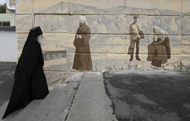 Orthodox monk Father Ioakim, 74, looks at a street graffiti, which displays Siberian characters of the 19th century including an Russian Orthodox monk, in Divnogorsk town outside Russia's Siberian city of Krasnoyarsk, September 30, 2013. The monk from a local parish came to the place to look at the artwork created by an unknown author and telling a story about an Orthodox priory which was replaced by the town for builders of Krasnoyarsk hydroelectric station in the middle of the 20th century and now called Divnogorsk town. (Photo by Ilya Naymushin/Reuters)