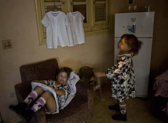 In this September 23, 2013 photo, six-year-old twins Asley and Aslen Velazquez get ready for school in Havana, Cuba. Their mother Tamara said she never expected to have twins from her first pregnancy and did not take fertility treatments. [It's a lot of work. It requires a lot of patience,] Velazquez said. [They are very active and dominant, although each has a different character]. (Photo by Ramon Espinosa/AP Photo)