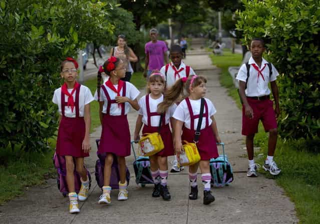 In this September 23, 2013 photo, from left to right, nine-year-old twins Camila and Carla Rodriguez, six-year-old twins Asley and Aslen Velazquez, and 11-year-old twin brothers Arian and Adrian Cueto walk together to school in Havana, Cuba. The twins are three sets of 12 living along two consecutive blocks in western Havana, ranging in age from newborns to senior citizens. (Photo by Ramon Espinosa/AP Photo)